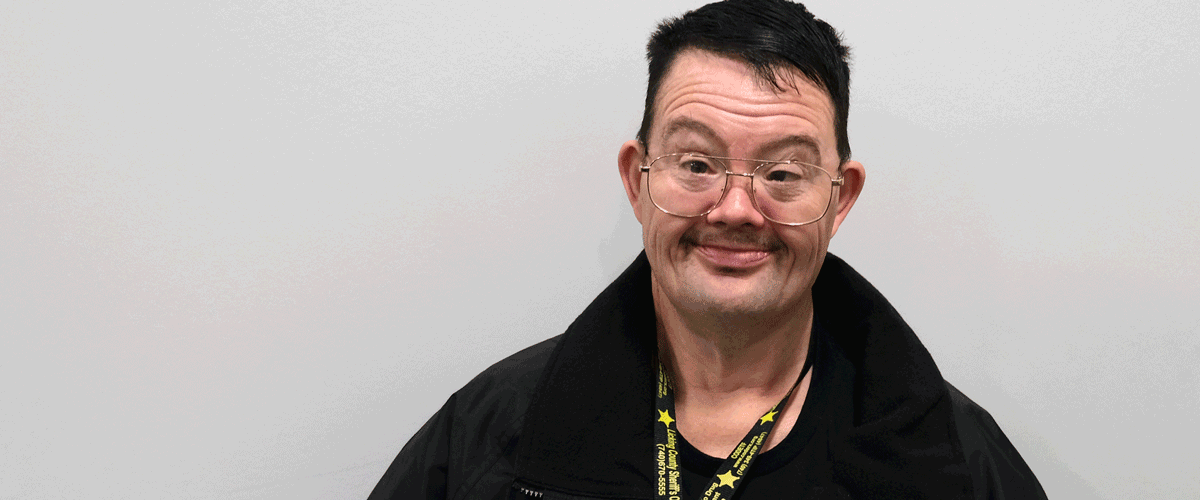 A man with dark hair and glasses smiles at the camera. He is wearing a black jacket and a Licking County Sheriff's Office lanyard.