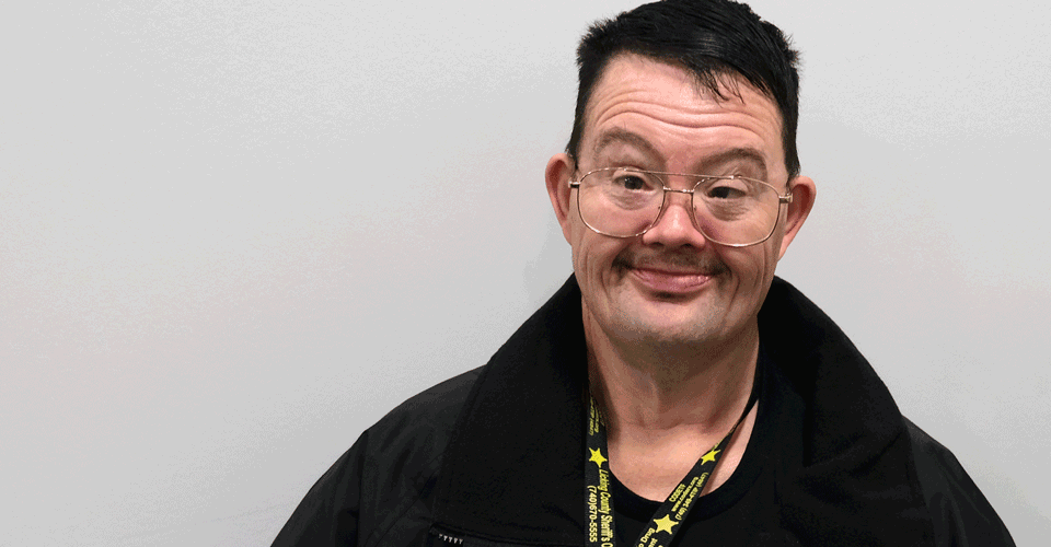 A man with dark hair and glasses smiles at the camera. He is wearing a black jacket and a Licking County Sheriff's Office lanyard.