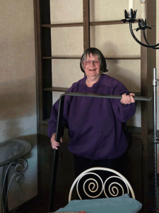 A woman in a dark purple shirt holds a curved, dark colored piece of metal.