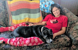 A woman sitting on a couch with a big brown dog laying in her lap.