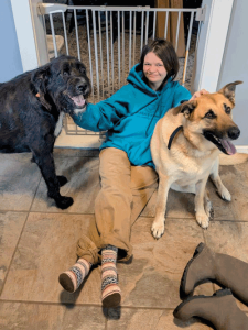 A woman sitting on the floor petting two large dogs.