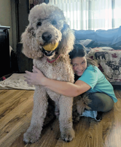 A woman hugging a large dog with fluffy hair.