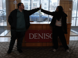 A young man and a young woman do a silly high five with smiles on their faces.