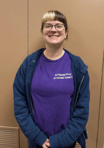 A woman wearing a Gathering Place shirt poses for a photo.