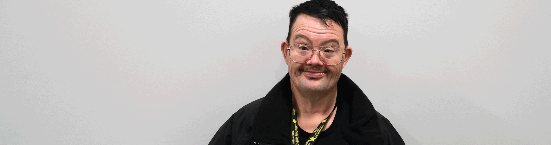 A man with dark hair and glasses smiles at the camera. He is wearing a black jacket and a Licking County Sheriff's Office lanyard.